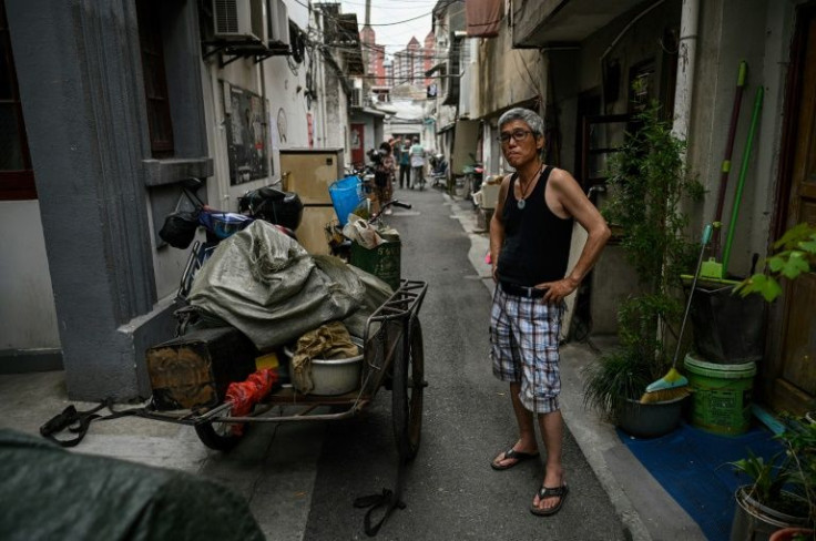 A man looks on in an alley as other Laoximen residents move furniture out of their soon-to-be-demolished homes