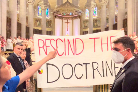 Indigenous people hold a banner against the discovery doctrine during a Mass presided over by Pope Francis at the Shrine of Sainte-Anne-de-Beaupre, Quebec, Canada July 28, 2022 in this still image obtained from social media. Chelsea Brunelle/via REUTERS  
