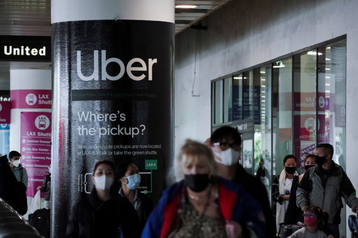 An Uber advertisement is seen behind travelers exiting the baggage claim area at the United Airlines terminal at Los Angeles International Airport (LAX) in Los Angeles, California, U.S., December 22, 2021.
