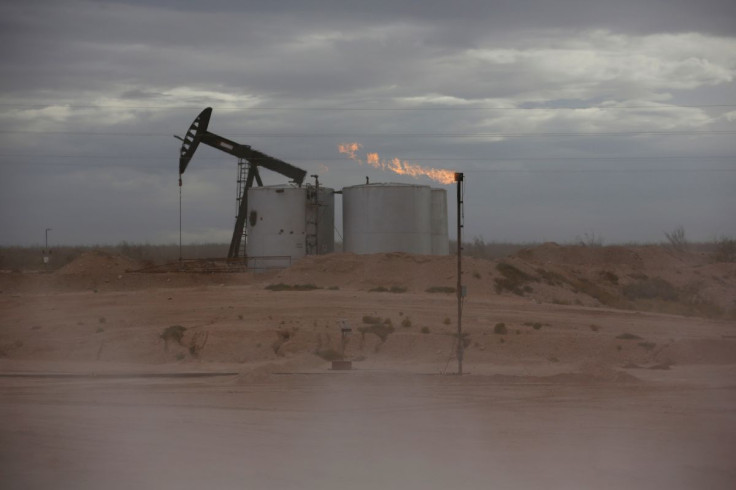 Dust blows around a crude oil pump jack and flare burning excess gas at a drill pad in the Permian Basin in Loving County, Texas, U.S. November 25, 2019. Picture taken November 25, 2019.