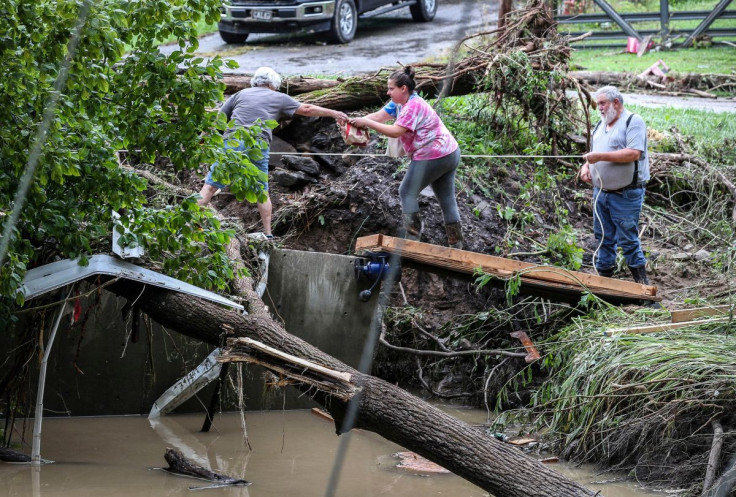 Tonya Smith, whose trailer was washed away by flooding, reaches for food from her mother Ollie Jean Johnson to give to Smith's father, Paul Johnson, as the trio used a rope to hang on over a swollen Grapevine Creek in Perry County, Kentucky, U.S. July 28,