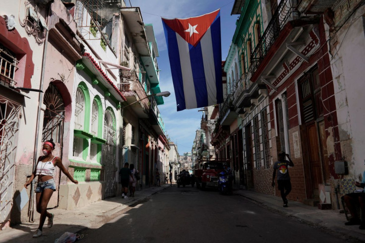People walk under a Cuban flag hanging in downtown Havana, Cuba, October 8, 2021. 