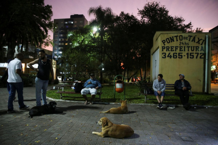 Homeless people with their pets wait for a bus to transfer to a shelter as low temperatures hit the streets, in Canoas, Brazil July 26, 2022.