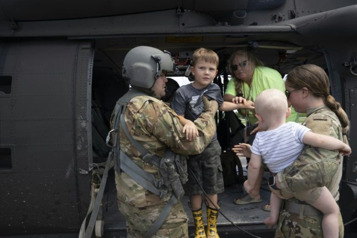 Sergeant Thorin Brant of the Kentucky National Guard carries children from a helicopter after they were airlifted from South Fork, Kentucky during a recon and rescue mission on July 30, 2022
