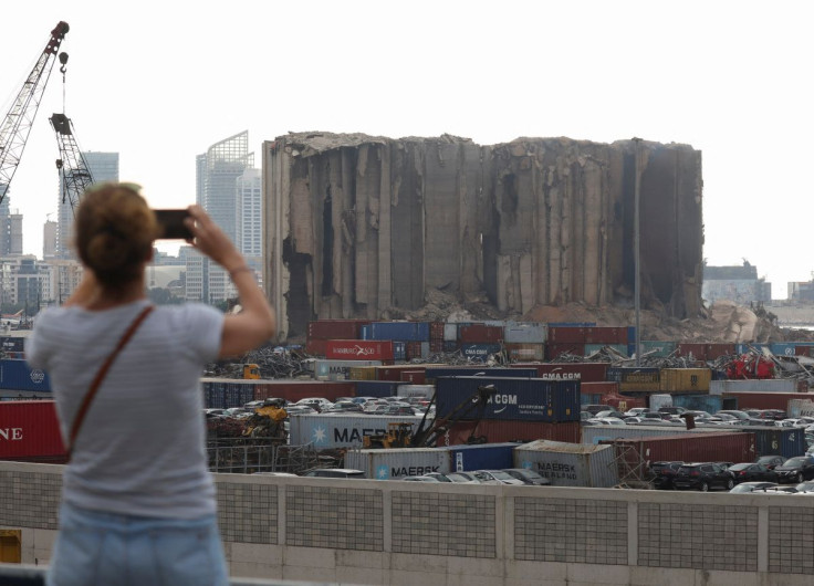A woman uses her phone near the partially-collapsed Beirut grain silos, damaged in the August 2020 port blast, in Beirut Lebanon July 31, 2022.