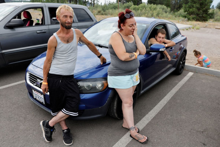Chad Butterfield, Tamara Butterfield and Frankie Romero stay outside an evacuation shelter after being evacuated from Yreka due to the McKinney Fire, in Weed, California, U.S., July 31, 2022.