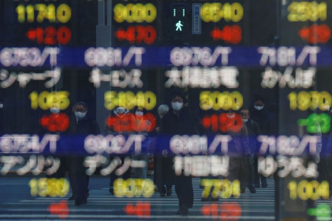 FILE PHOTO - Pedestrians wearing protective masks, amid the coronavirus disease (COVID-19) outbreak, are reflected on an electronic board displaying various companyâs stock prices outside a brokerage in Tokyo, Japan, February 25, 2022. 