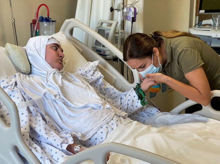 Nassma Cheaito, kisses the hand of her sister, Liliane Cheaito who is mostly paralyzed from August 2020 Beirut port blast, as she lies on hospital bed at the American University of Beirut Medical Center (AUBMC) in Beirut, Lebanon July 26, 2022.