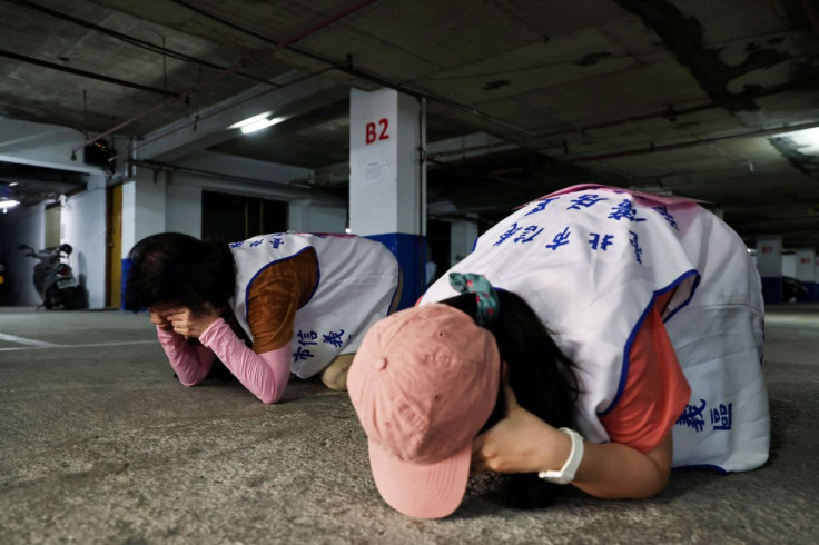 People demonstrate taking shelter with their hands covering their eyes and ears while keeping their mouth open, during a drill at a basement parking lot that will be used as an air-raid shelter in the event of an attack, in Taipei, Taiwan, July 22, 2022.