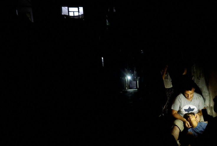 A Palestinian man sits with his son outside their house during a power cut amid a heatwave at Beach refugee camp in Gaza City August 1, 2022. 