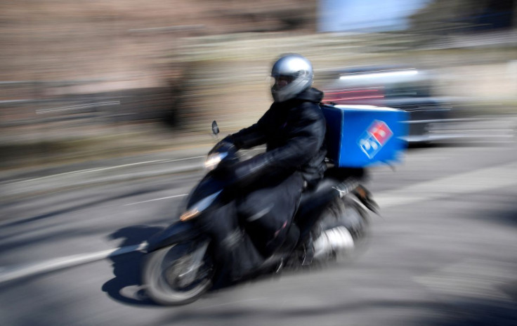 A Domino's pizza delivery driver rides a motorbike in a residential street in West London as the spread of the coronavirus disease (COVID-19) continues, in London, Britain, March 24, 2020. 