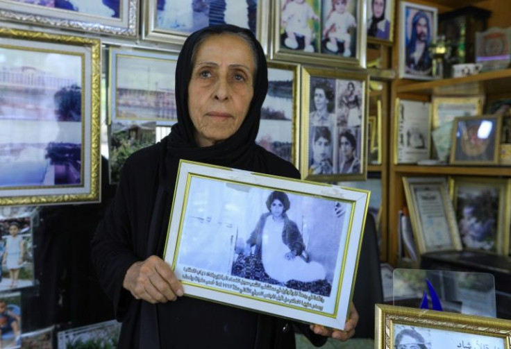 Photographer and ex-political prisoner Samira Mazaal, 77, poses with a framed picture of her on a hospital bed after being tortured