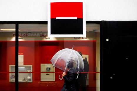 A person holds an umbrella as the logo of French Bank Societe Generale is seen outside a bank building in Saint-Sebastien-sur-Loire near Nantes, France, May 4, 2021. 