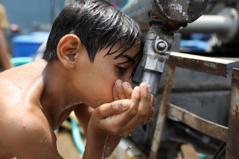 A boy drinks water from a municipal tanker on a hot summer day in New Delhi, India, May 1, 2022. 