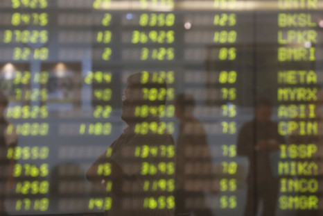 A man stands near an electronic board showing the stock market index at the Bank Mandiri Sekuritas trading floor in Jakarta November 25, 2015.   