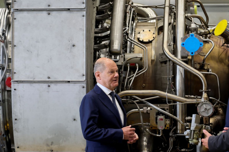 German Chancellor OIaf Scholz stands next to a gas turbine meant to be transported to the compressor station of the Nord Stream 1 gas pipeline in Russia during his visit to Siemens Energy's site in Muelheim an der Ruhr, Germany, August 3, 2022. 