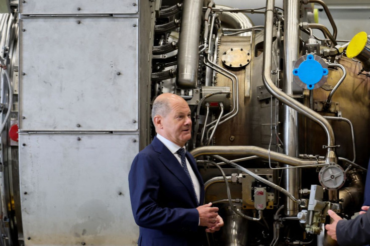 German Chancellor OIaf Scholz stands next to a gas turbine meant to be transported to the compressor station of the Nord Stream 1 gas pipeline in Russia during his visit to Siemens Energy's site in Muelheim an der Ruhr, Germany, August 3, 2022.