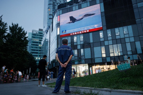 A man watches a CCTV news broadcast, showing a fighter jet during joint military operations near Taiwan by the Chinese People's Liberation Army's (PLA) Eastern Theatre Command, at a shopping center in Beijing, China, August 3, 2022. 