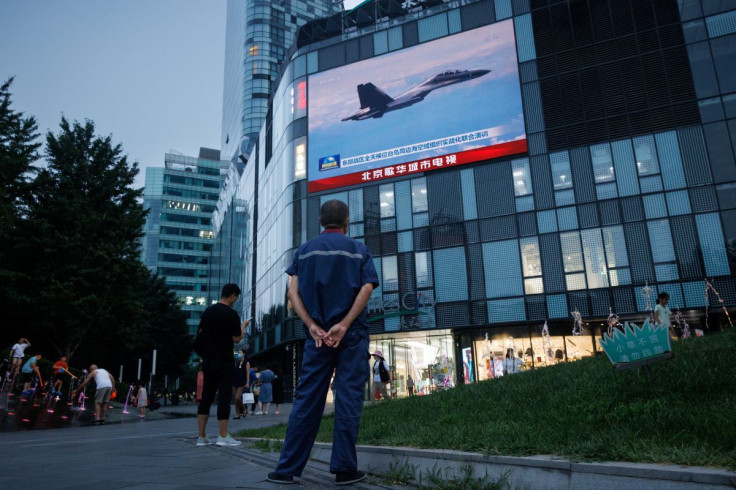 A man watches a CCTV news broadcast, showing a fighter jet during joint military operations near Taiwan by the Chinese People's Liberation Army's (PLA) Eastern Theatre Command, at a shopping center in Beijing, China, August 3, 2022.