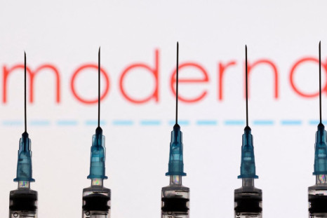 Syringes with needles are seen in front of a displayed Moderna logo in this illustration taken November 27, 2021. 