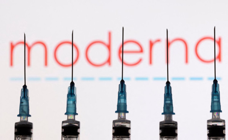 Syringes with needles are seen in front of a displayed Moderna logo in this illustration taken November 27, 2021.