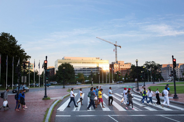 Migrants cross Massachusetts Avenue towards Washington Union Station after completing a bus ride from Texas, near the U.S. Capitol in Washington, U.S., July 30, 2022.