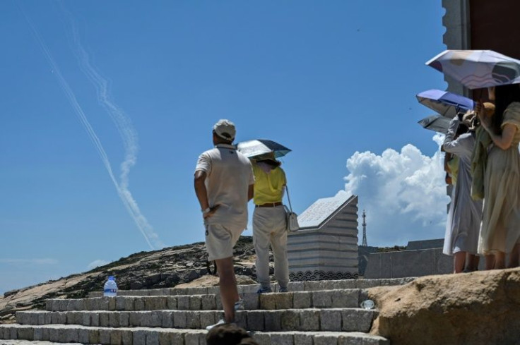 Smoke trails from projectiles launched by the Chinese military are seen as tourists look on from Pingtan island, China