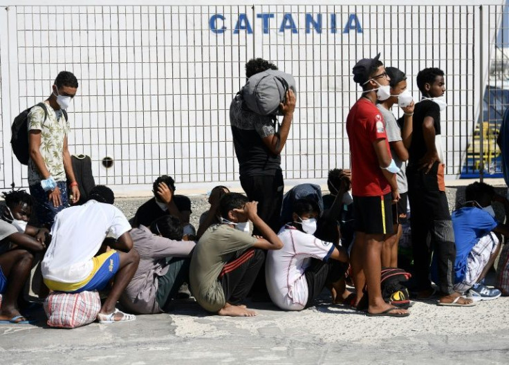 Migrants wait to board a ferry from the island of Lampedusa to Sicily