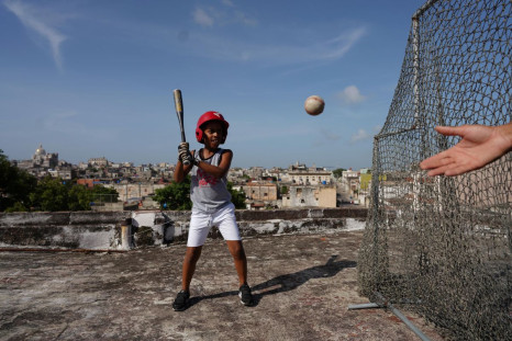 Baseball fan Kevin Kindelan, 8, practices with his father on the roof of their house in Havana, Cuba, June 14, 2022. Kindelan says he wants to play for Cuba's national baseball club.  