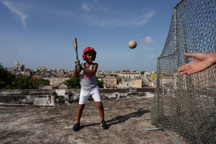 Baseball fan Kevin Kindelan, 8, practices with his father on the roof of their house in Havana, Cuba, June 14, 2022. Kindelan says he wants to play for Cuba's national baseball club.