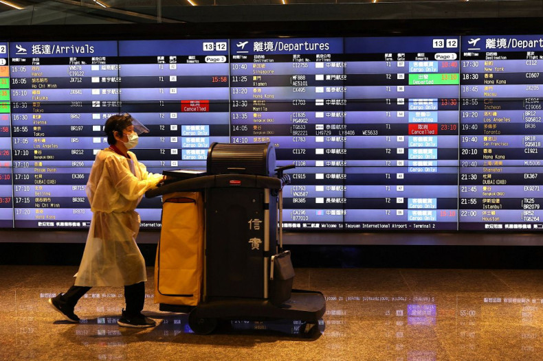 A airport staff walks past a board showing departure statuses at Taoyuan International Airport in Taoyuan City, Taiwan, August 4, 2022. 