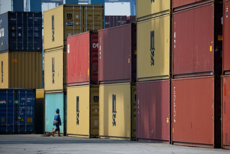 A worker carrying a broom passes stacks of containers at the IPC Containter Terminal of Tanjung Priok port in Jakarta, Indonesia, November 4, 2021. 