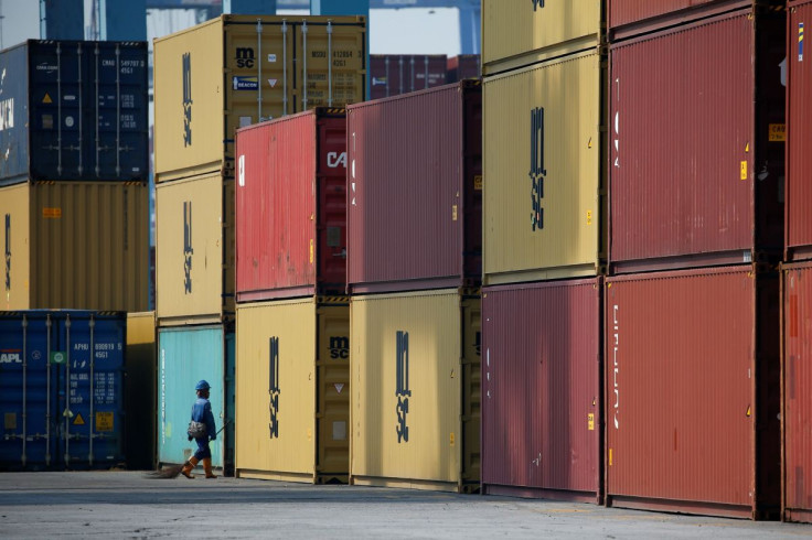 A worker carrying a broom passes stacks of containers at the IPC Containter Terminal of Tanjung Priok port in Jakarta, Indonesia, November 4, 2021. 