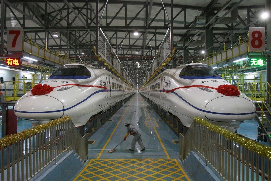 A labourer cleans the floor beside a China Railway High-speed CRH train preparing for the operation ceremony from Wuhan to Guangzhou in Wuhan, Hubei province, in this December 26, 2009