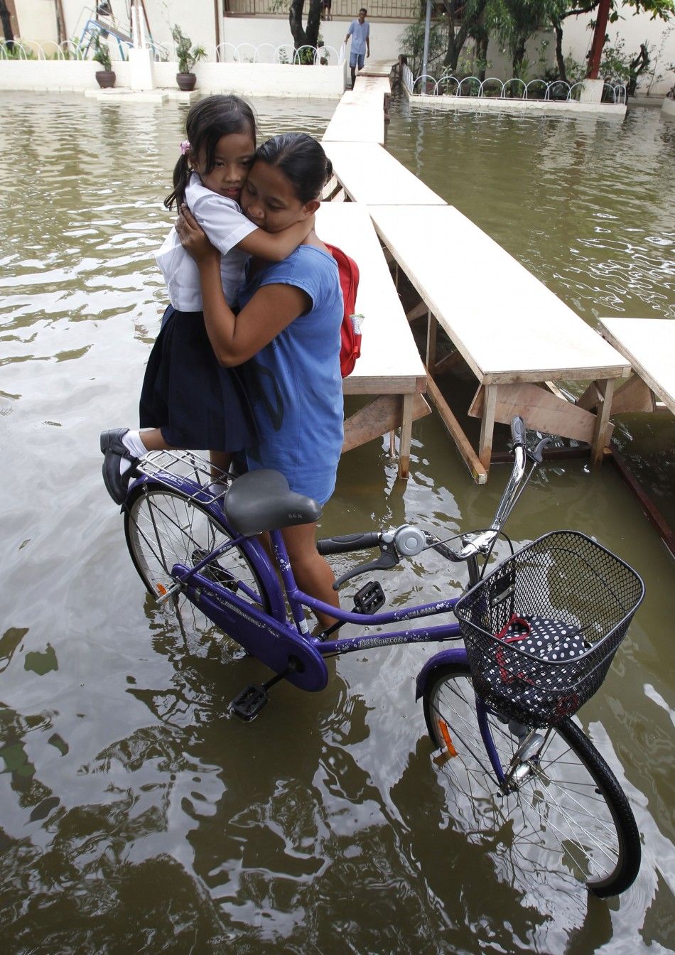 A woman carries her daughter across a flooded area brought by Typhoon Sepat in Valenzuela city