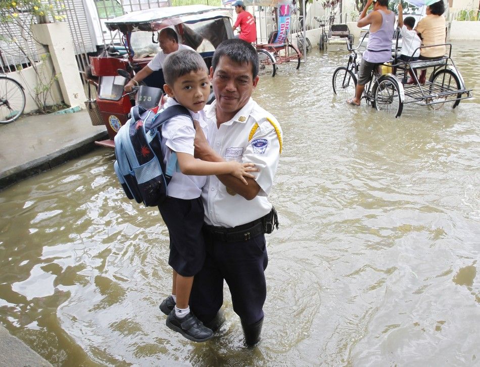 A security guard carries a school boy across a flooded area brought by Typhoon Sepat in Valenzuela city