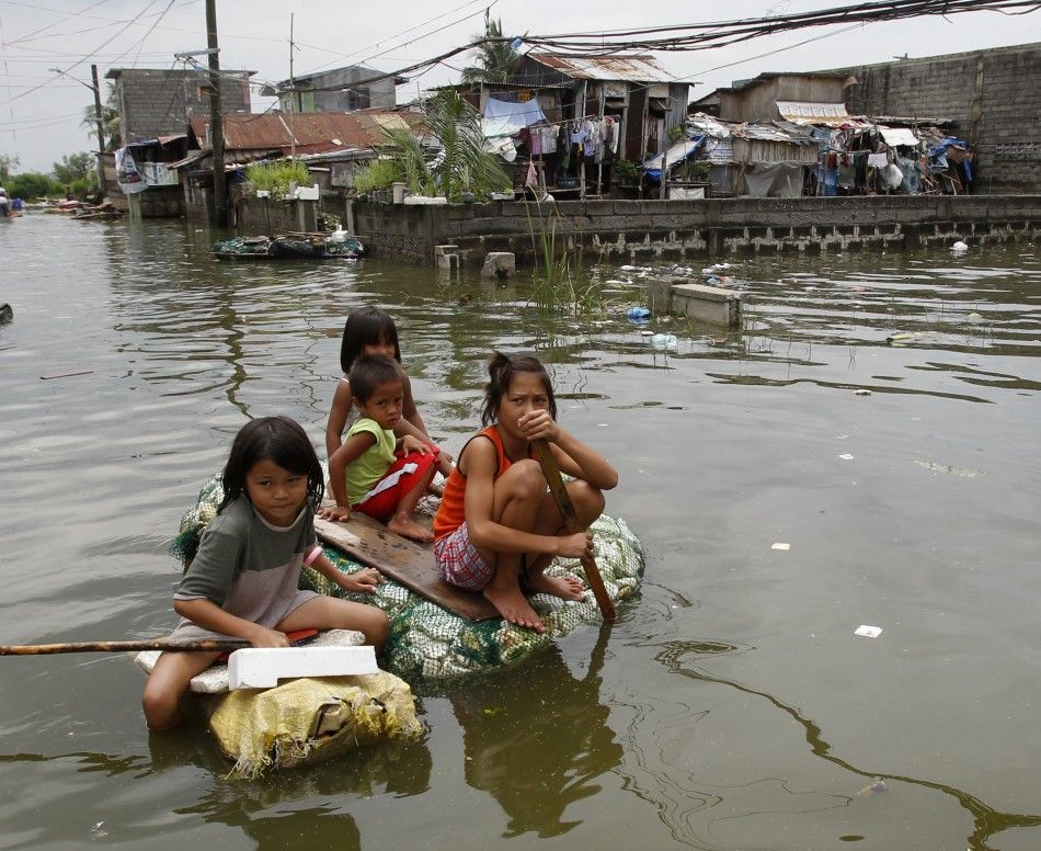 Residents travel on makeshift rafts in a flooded residential area in Malabon