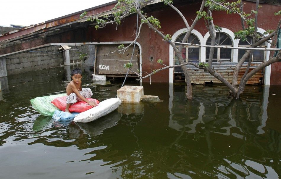 A boy rides on a makeshift raft in a flooded residential area in Malabon