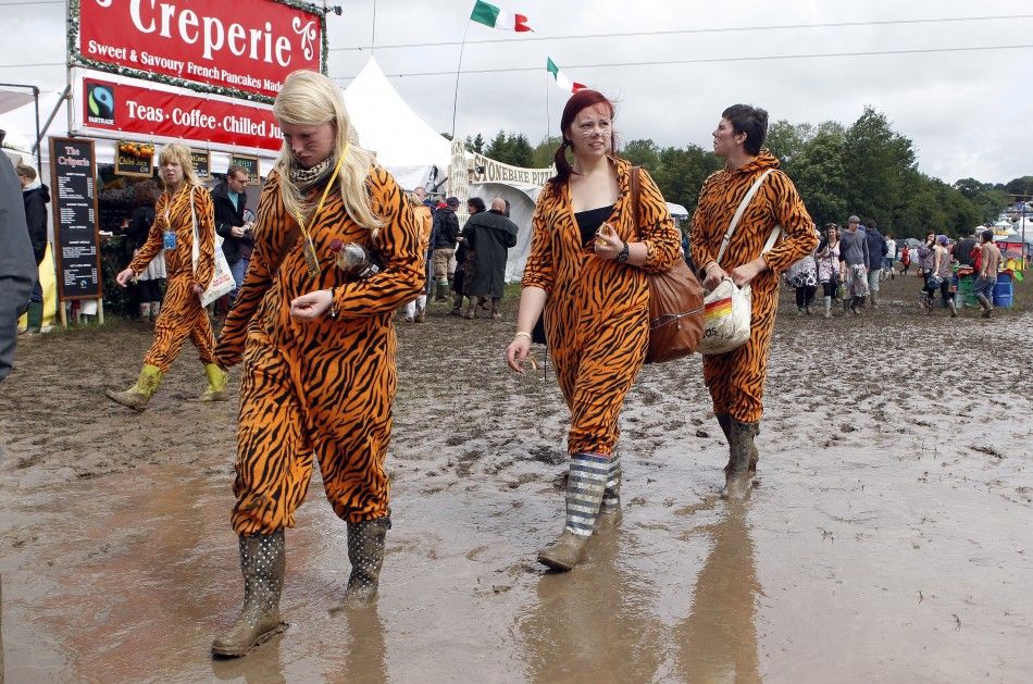 Glastonbury revelers get into festive spirits despite adverse weather conditions.