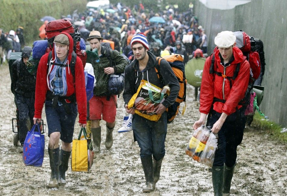 Glastonbury revelers get into festive spirits despite adverse weather conditions.