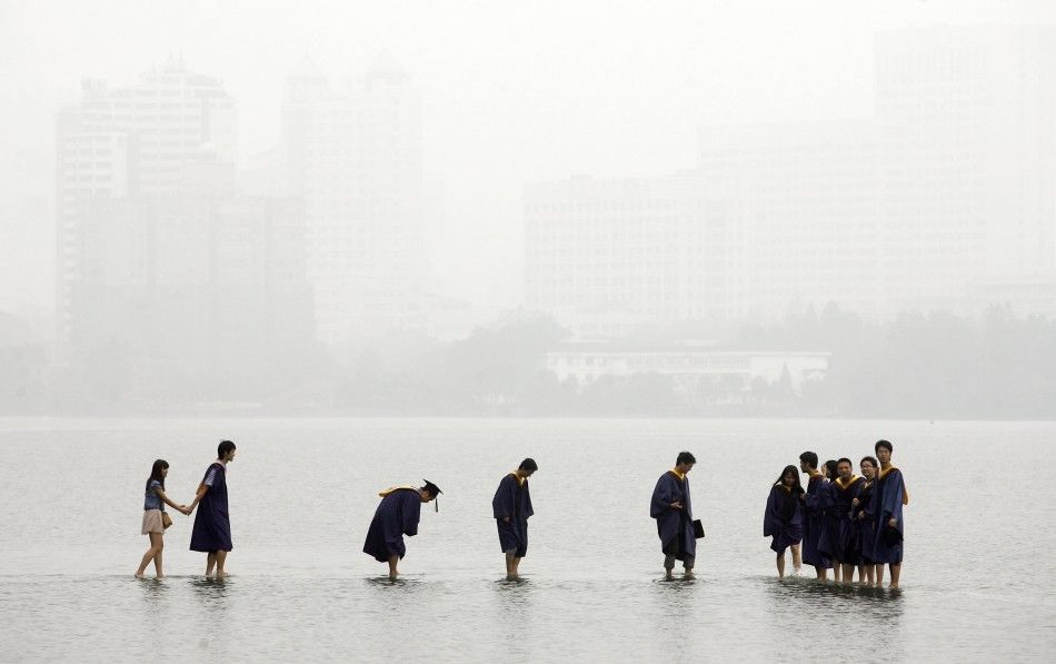 Students in graduation robes stand on a stone bridge submerged underwater at the flooded Donghu Lake in Wuhan, Hubei province, June 21, 2011.