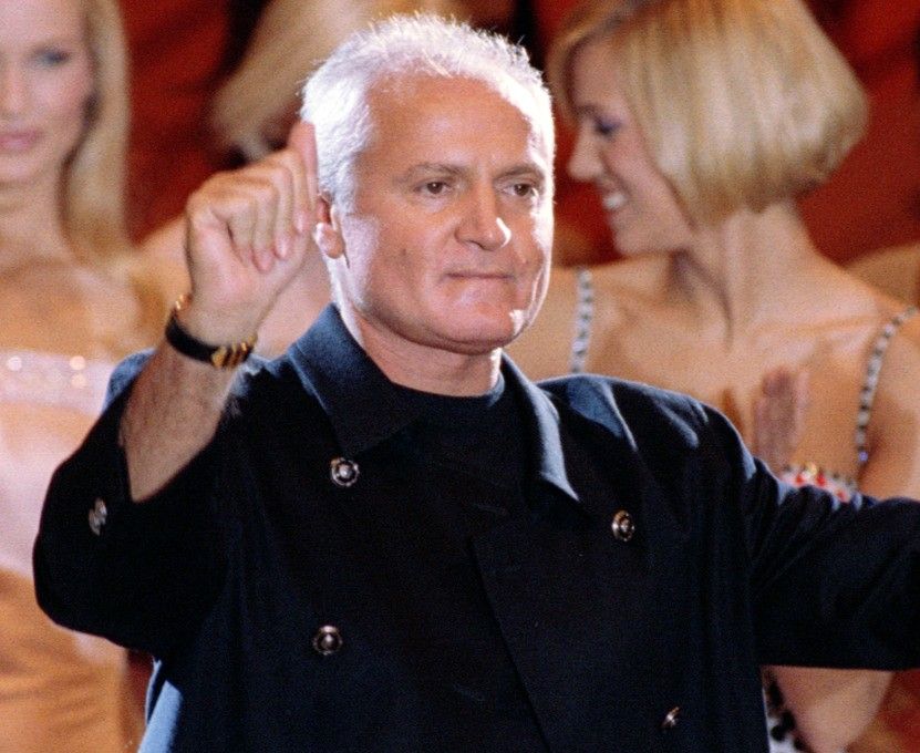 Italian designer Gianni Versace greets the audience as the models applaud following the presentation..