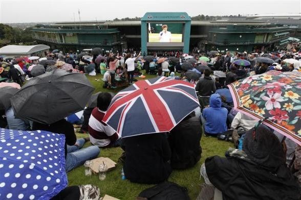Spectators hold umbrellas as they sit on Murrays Mount 