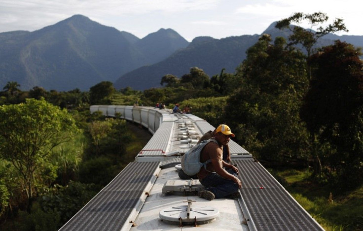 Honduran immigrants ride on the top of a freight train