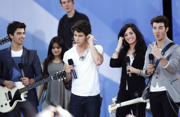 Jonas Brothers (L-R) Joe, Nick, and Kevin smile on stage with Lovato before performing in Central Park
