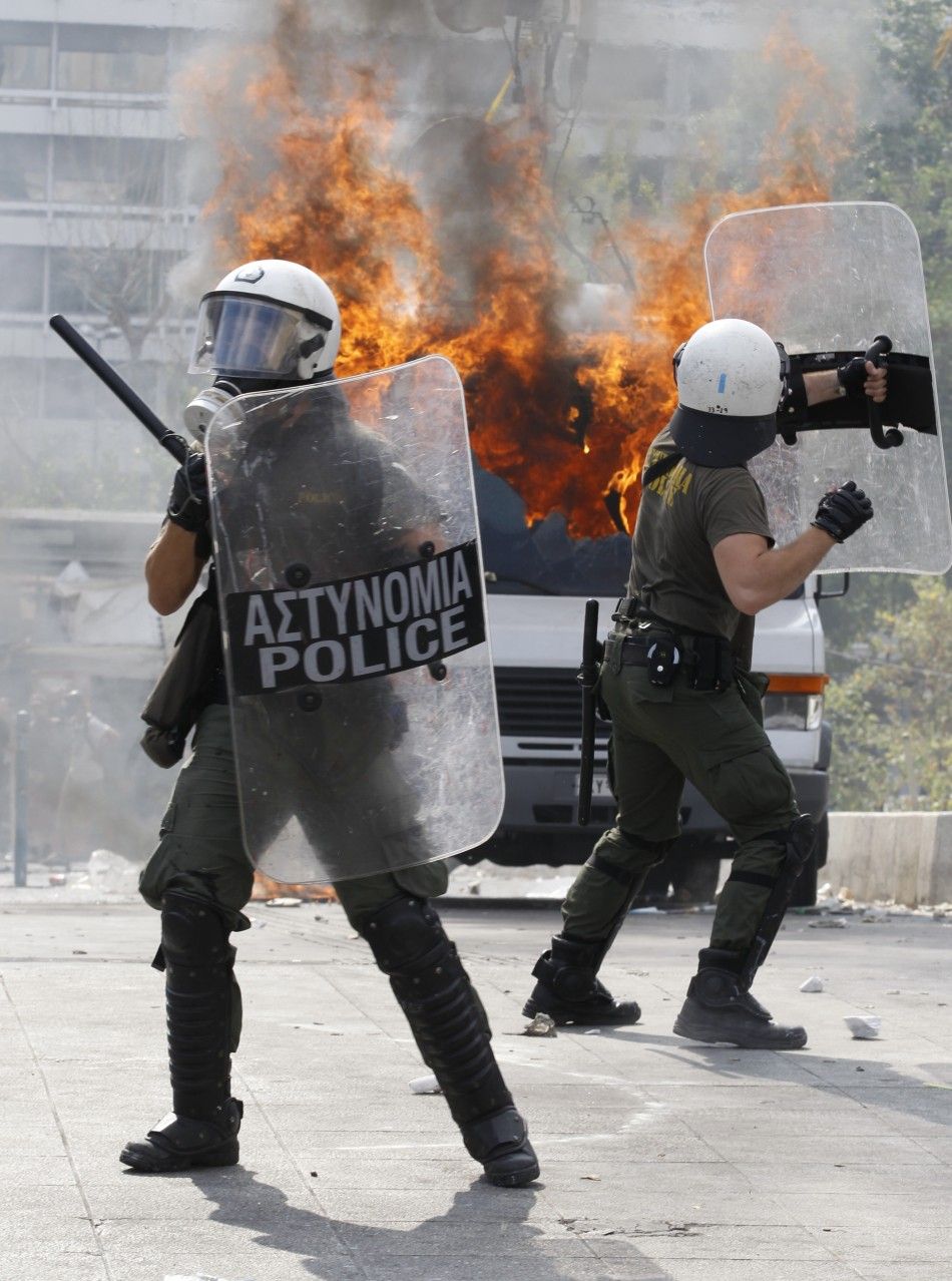Riot police take cover from projectiles during protests against austerity measures in Athens