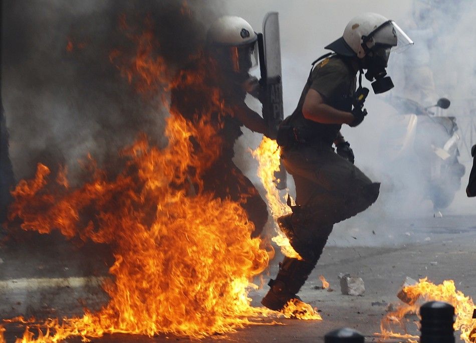 Riot police advance through flames during protests against austerity measures in Athens