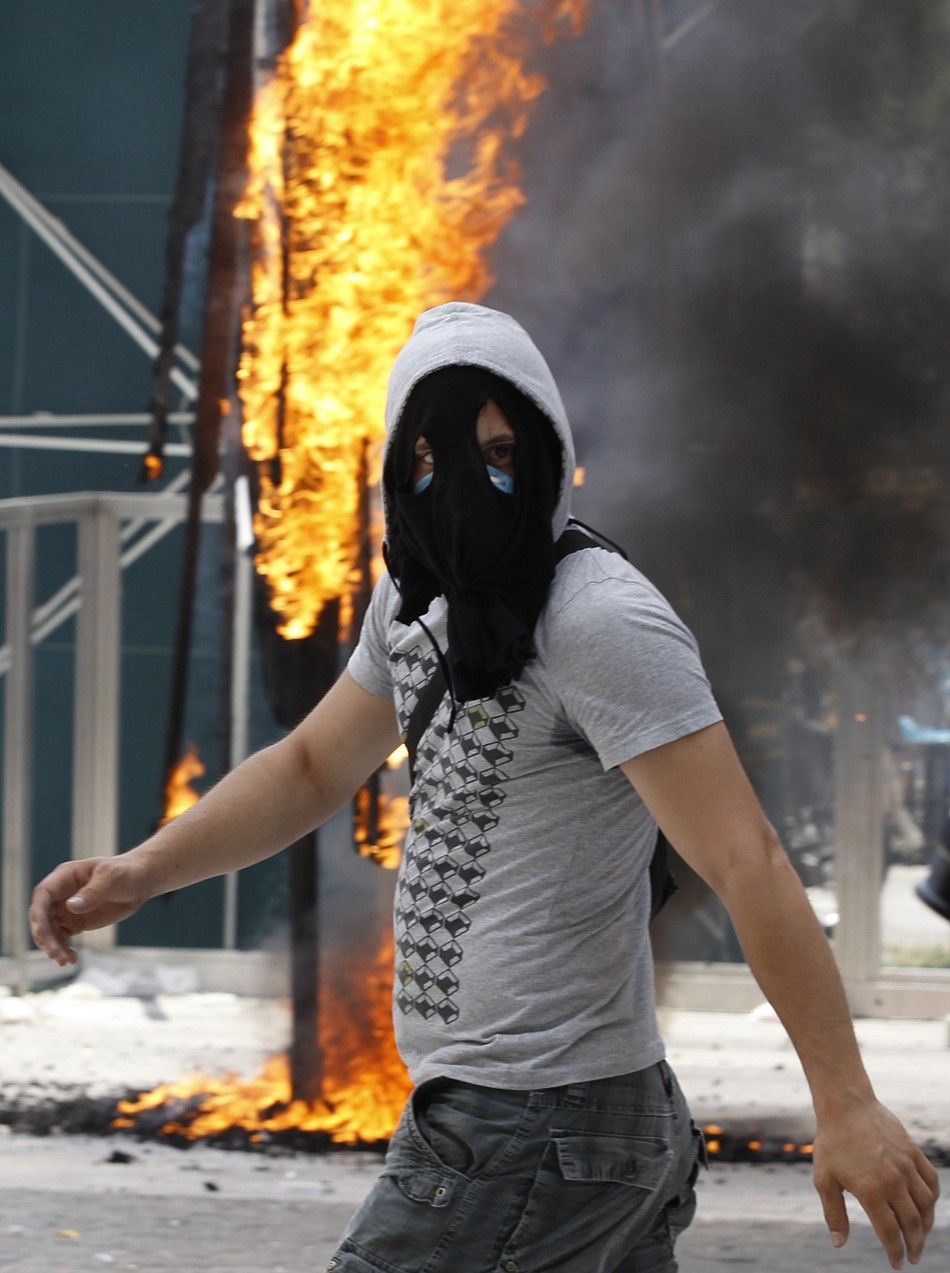 A demonstrator passes a burning parasol during protests against austerity measures in Athens