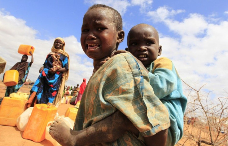 A Somali refugee child who recently arrived at the Dagahaley camp cries while carrying a sibling, in Dadaab