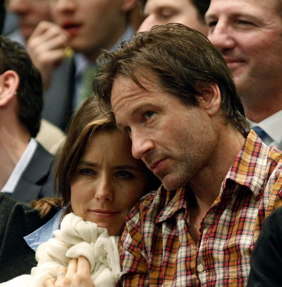 Actor David Duchovny sits with his wife, actress Tea Leoni, as they watch former world number one Andre Agassi and 14-time grand slam champion Pete Sampras play their exhibition match at the BNP Paribas Showdown at Madison Square Garden in New York Februa